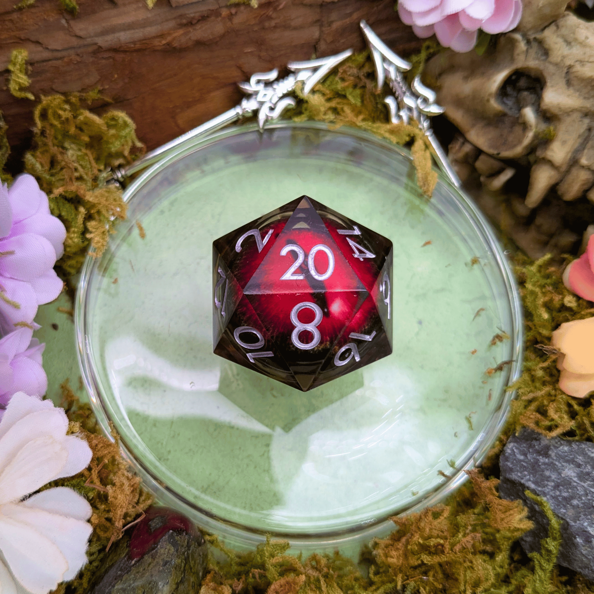 Red polyhedral dice with white numbers in a glass container surrounded by flowers and nature elements
